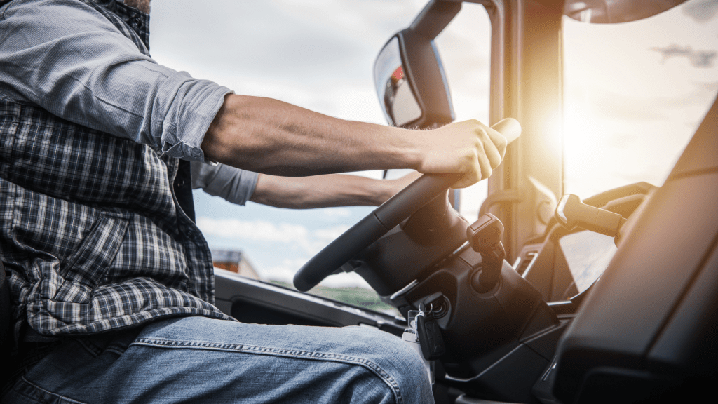 Conducteur de camion concentré, naviguant sur la route tout en gérant les commandes dans la cabine de son véhicule.